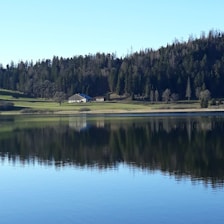 A cozy lakefront home bathed in warm sunlight, reflecting peaceful water and inviting greenery.