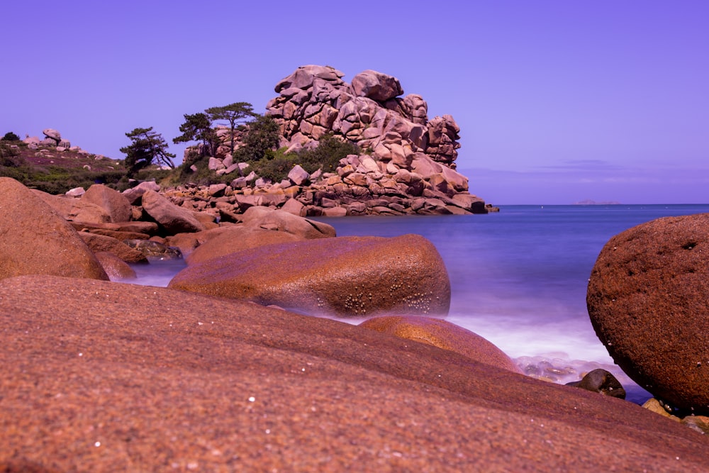 a rocky beach with a body of water in the background