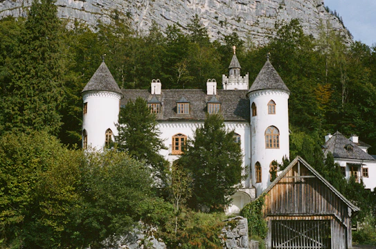 a large white building with towers surrounded by trees