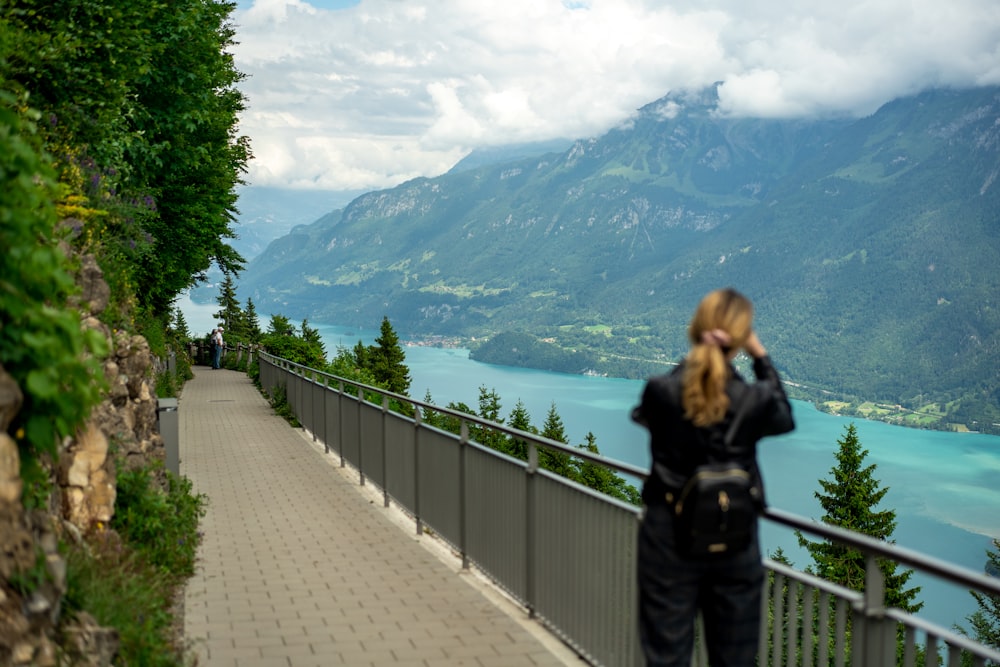 a person standing on a bridge looking at a lake and mountains