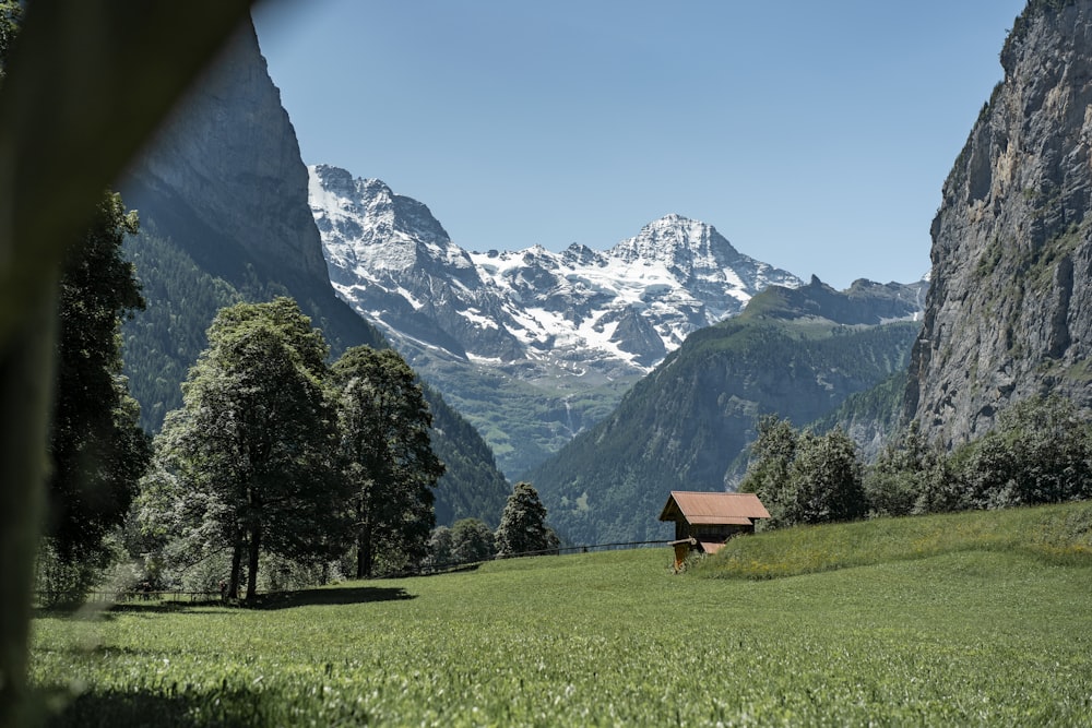 a small house in a grassy field with mountains in the background