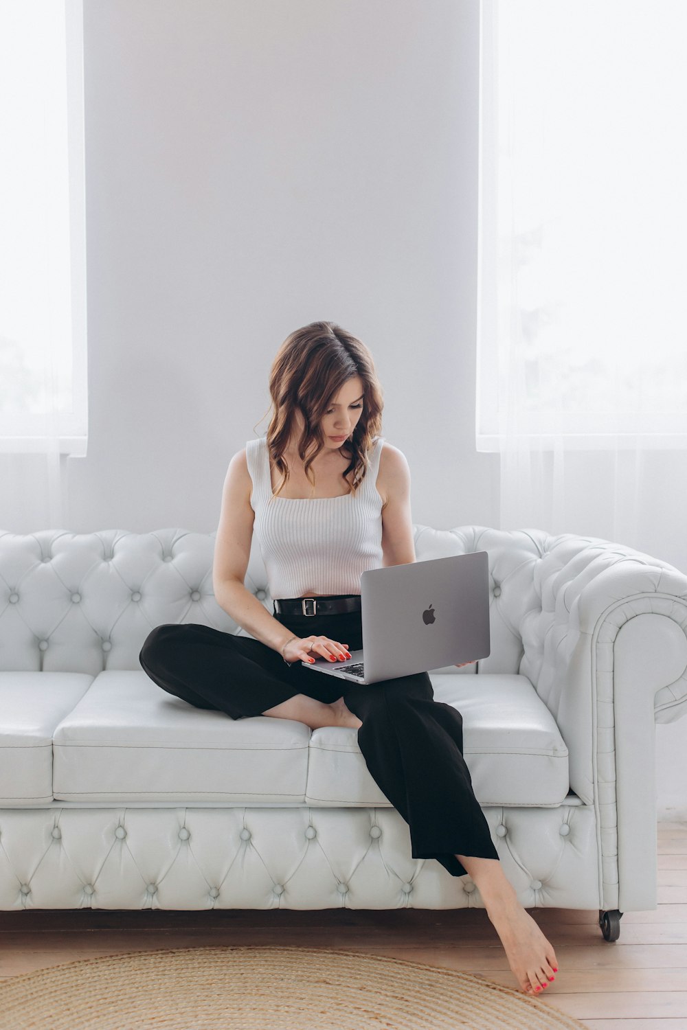 Eine Frau sitzt mit einem Laptop auf einer Couch