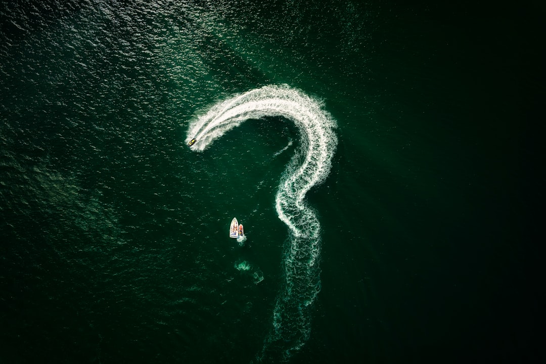 a person swimming in water, Open Question? A powerboat spelling it out in the costal waters of the Devon coastline, UK