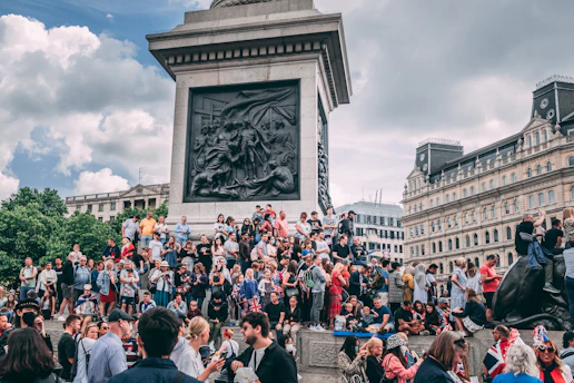 A lively group of people gathered around a historic monument during a sunny outing.