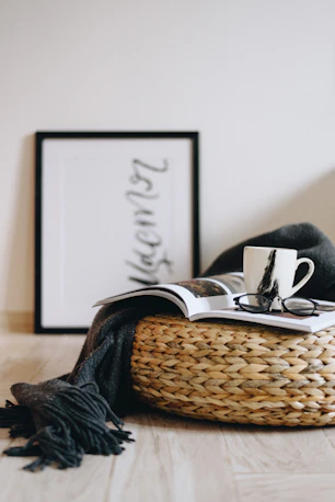 Cozy home scene with a coffee mug, glasses, magazine, blanket, and woven basket