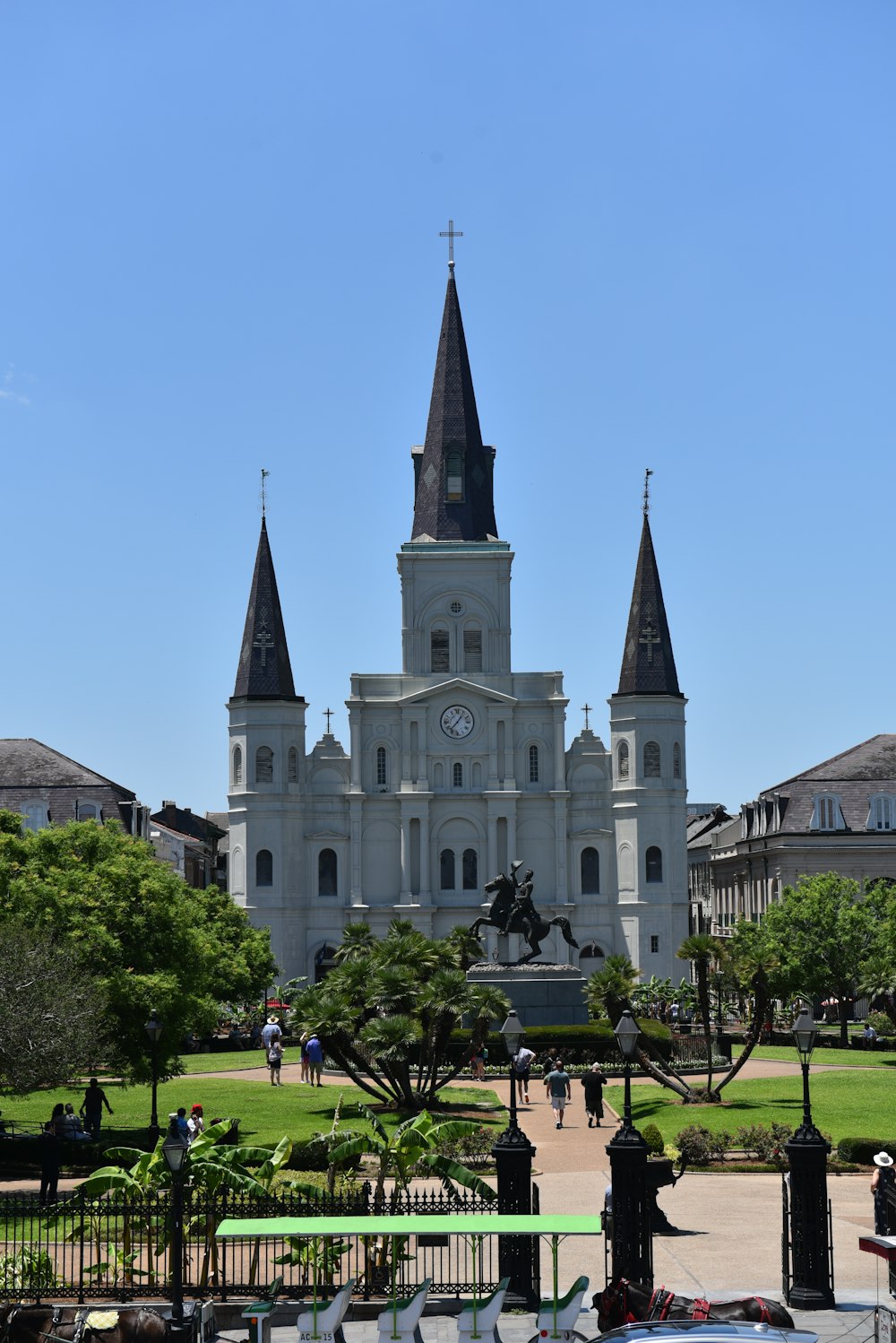 a large white building with a clock tower with St. Louis Cathedral in the background
