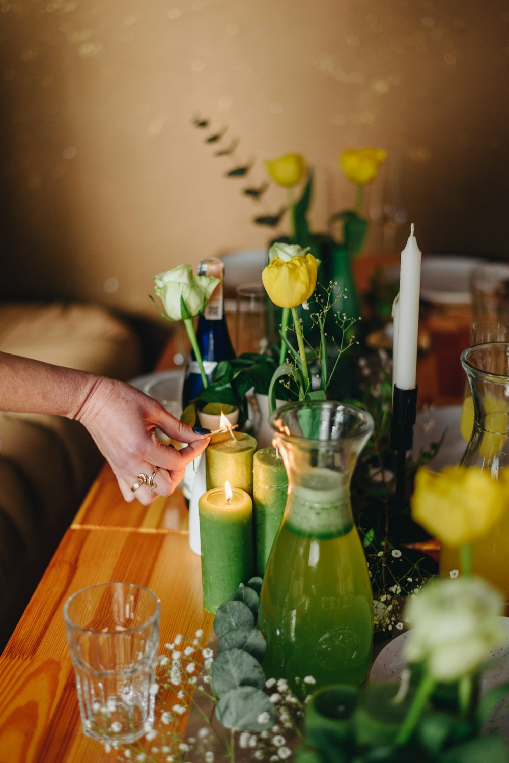 a hand holding a yellow flower next to a vase of yellow flowers