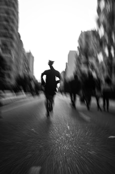 Runner sprinting through a bustling city street on asphalt, capturing motion and urban energy.