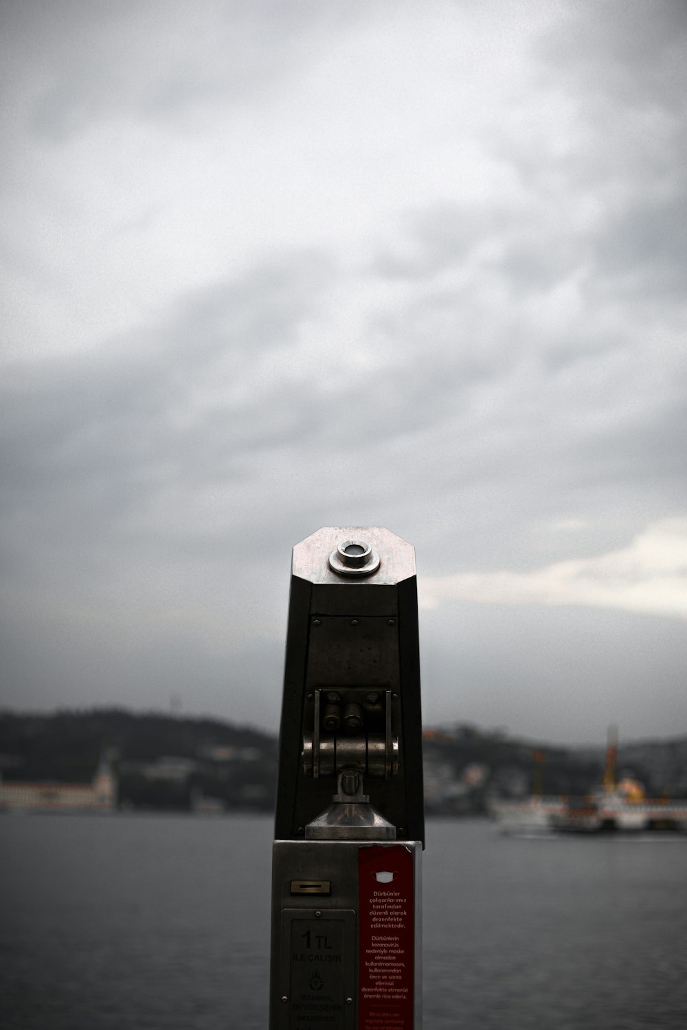 a black and silver object with a camera on it by water