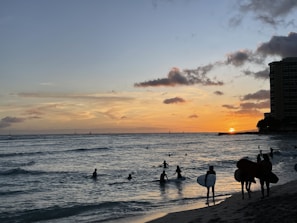Sunset over the Pacific Ocean from a beach in La Libertad, with surfers catching waves