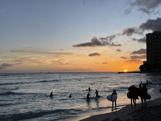 Sunset over the Pacific Ocean from a beach in La Libertad, with surfers catching waves