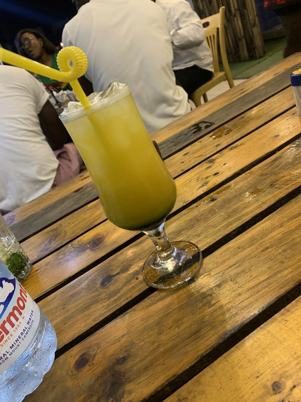 a glass of yellow liquid on a wooden table