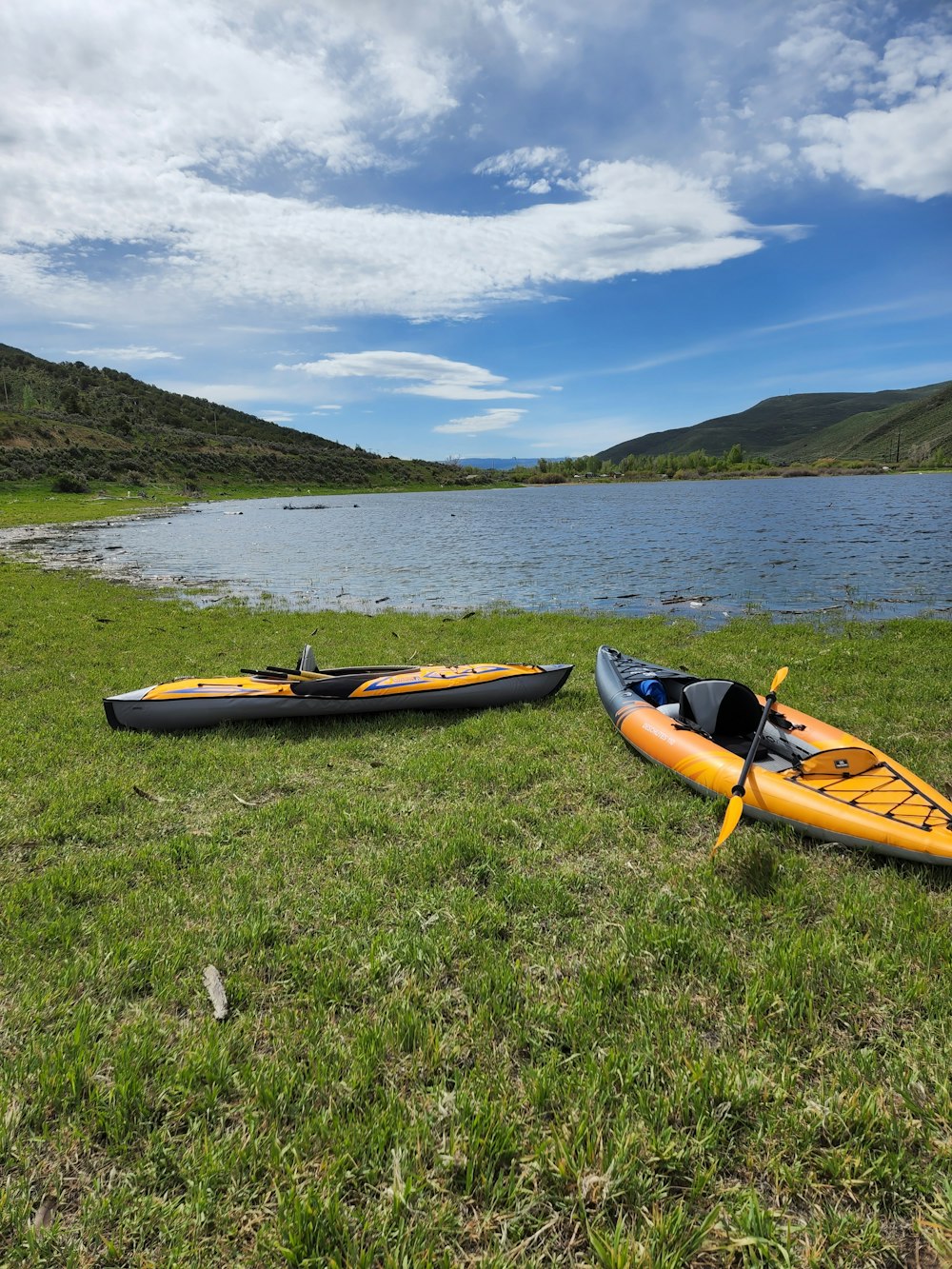 a couple of kayaks on grass by a body of water