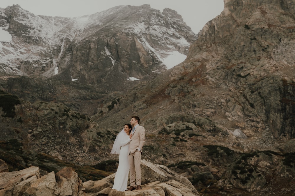 a man and woman kissing on a rocky mountain