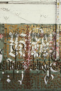 Close-up of layered graffiti calligraphy on a wooden panel, showing faded letters and textured paint.