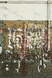 Close-up of layered graffiti calligraphy on a wooden panel, showing faded letters and textured paint.