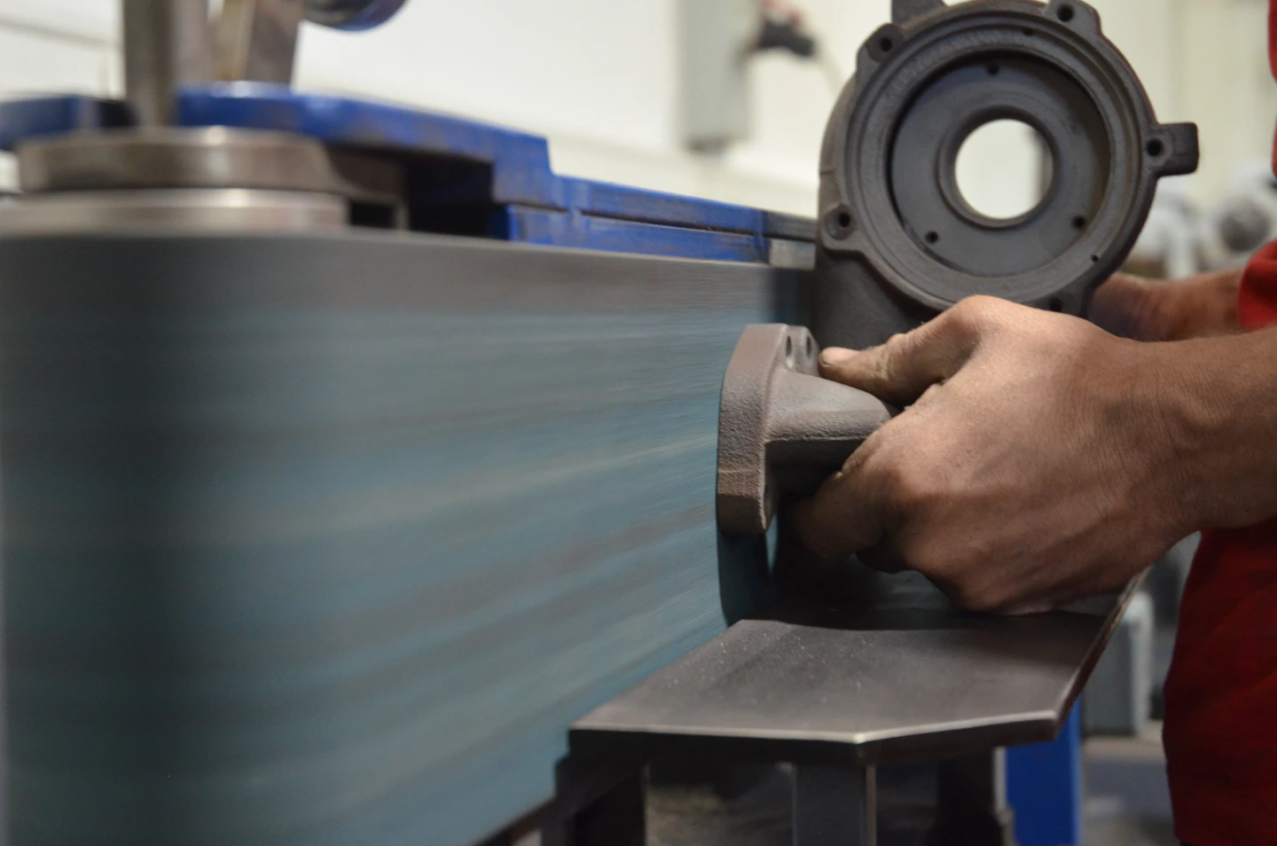 A technician holding a turbocharger compressor housing against a precision balancing wheel