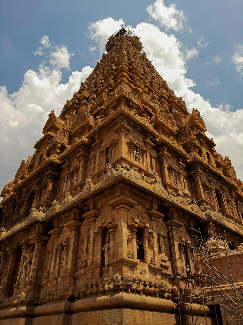 um edifício alto com muitas janelas com o Templo Brihadeeswarar ao fundo