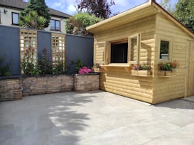 A site-built shed with clean lines and fresh paint, nestled beside a garden in a sunny yard.
