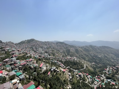 A panoramic view of green lots nestled in the natural hills of Altos de Villa Mancay under a clear blue sky.
