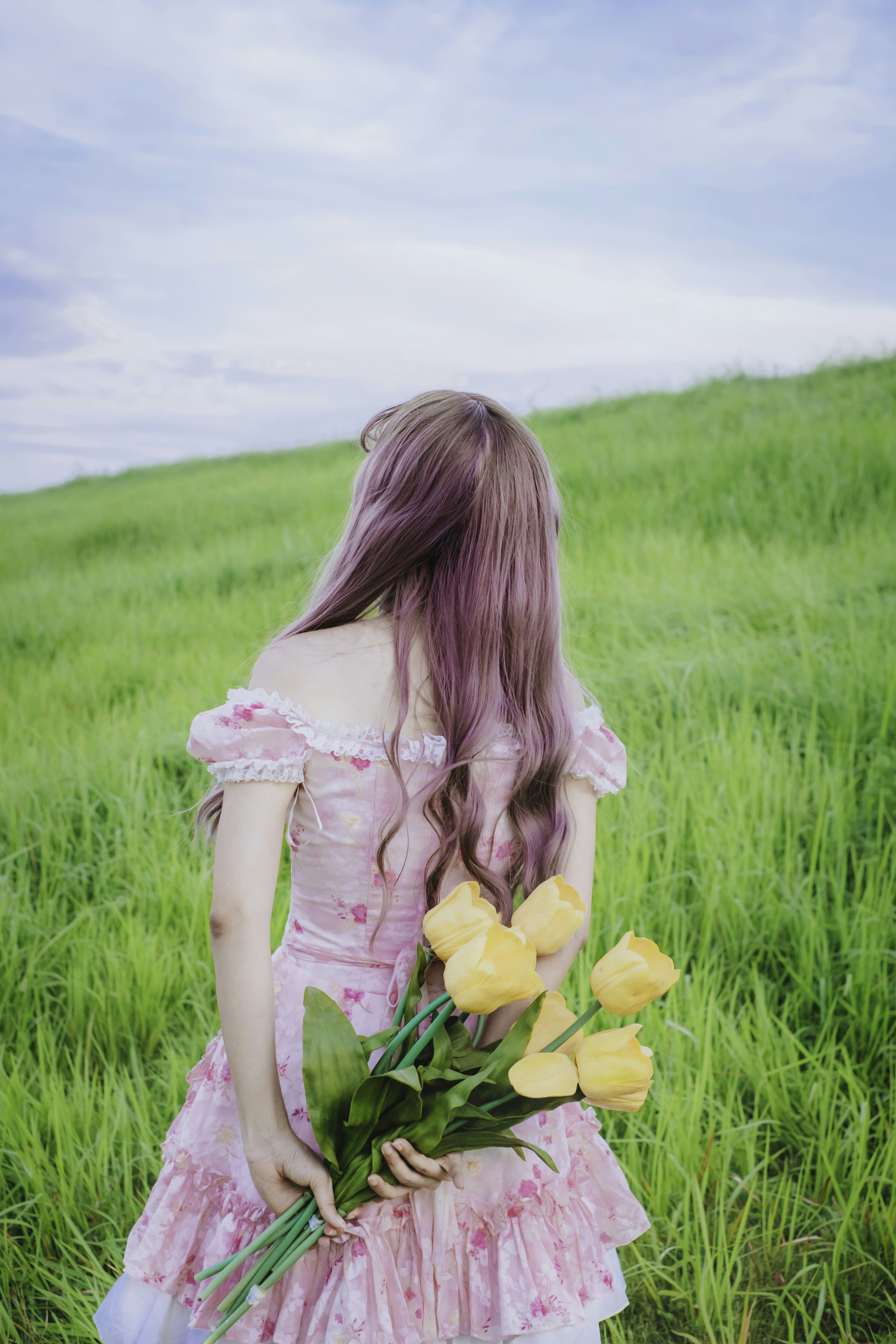 a person in a pink dress holding flowers in a field