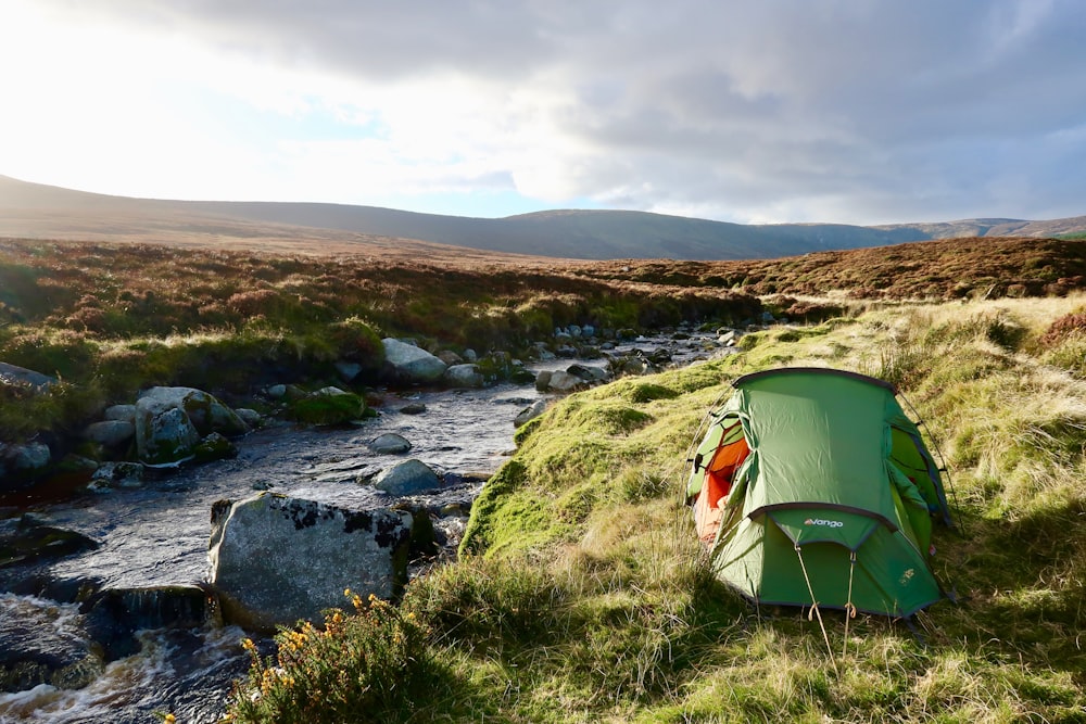 a tent on a grassy hill by a river