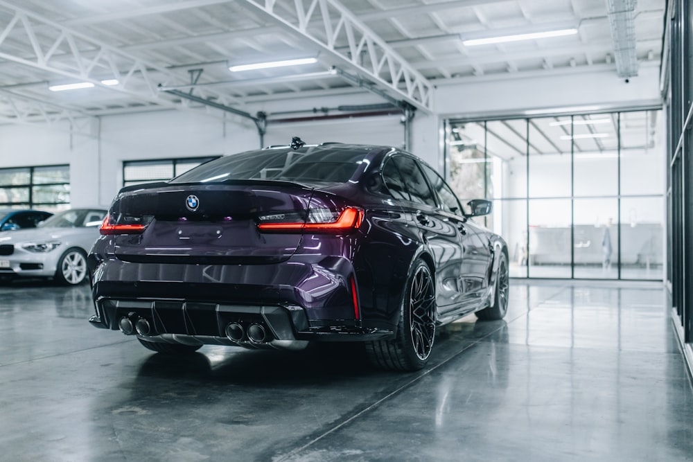 a black sports car parked in a large room with other cars