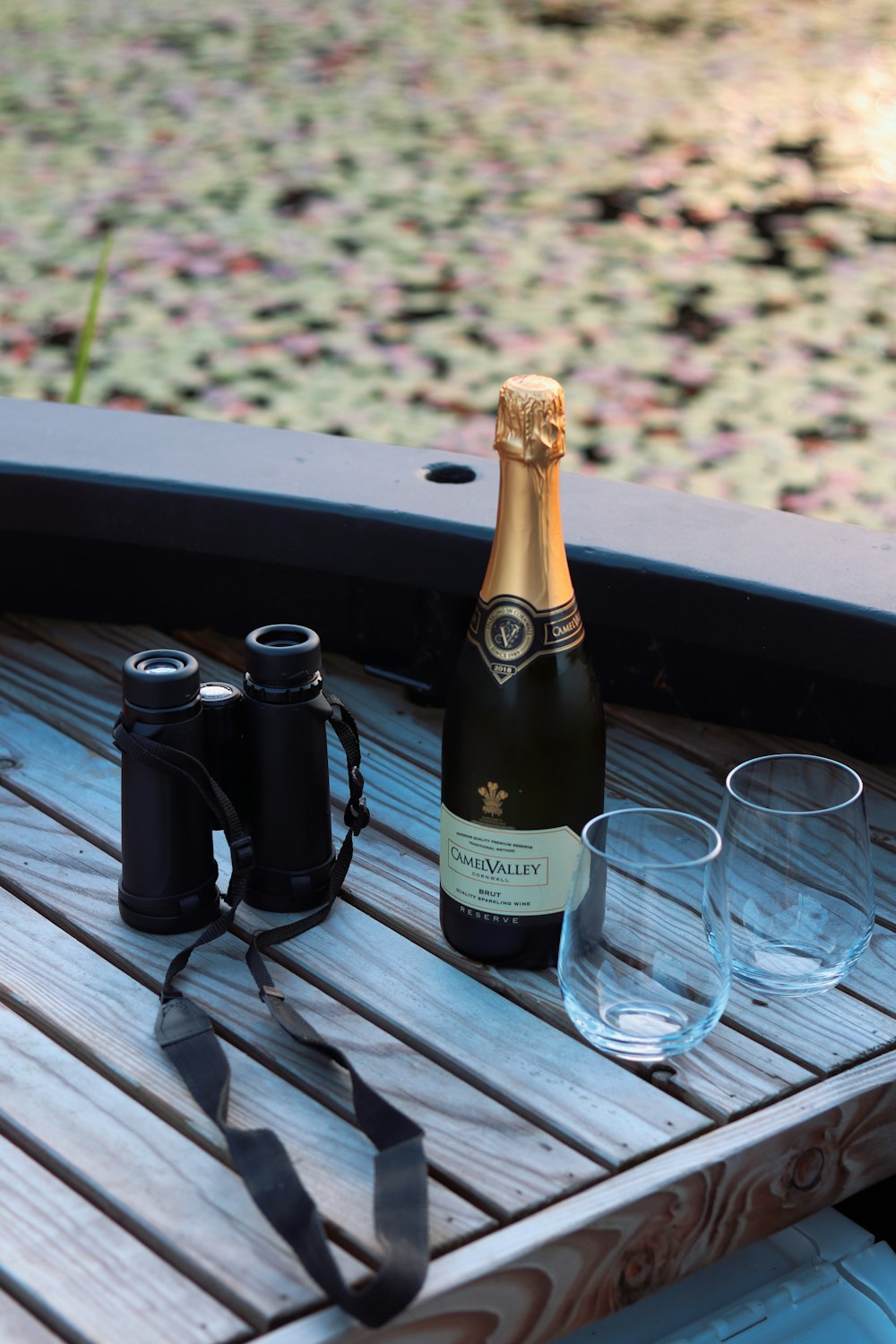 a bottle of alcohol and glasses on a picnic table