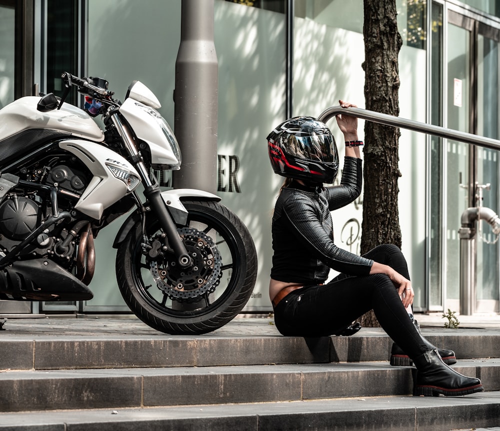 a person sitting on stairs next to a motorcycle