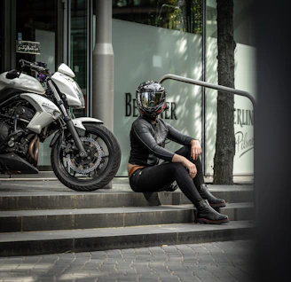 a person sitting on a curb next to a motorcycle
