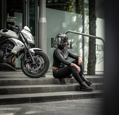 a person sitting on a curb next to a motorcycle