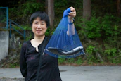 A joyful angler holding a freshly caught fish against a backdrop of rolling hills.