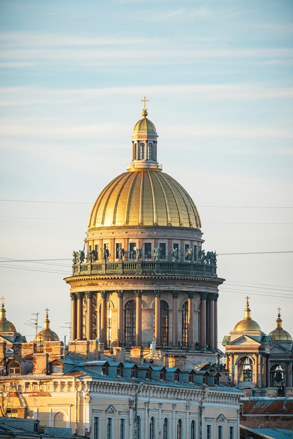 un grande edificio con un tetto a cupola d'oro con la Basilica di San Pietro sullo sfondo