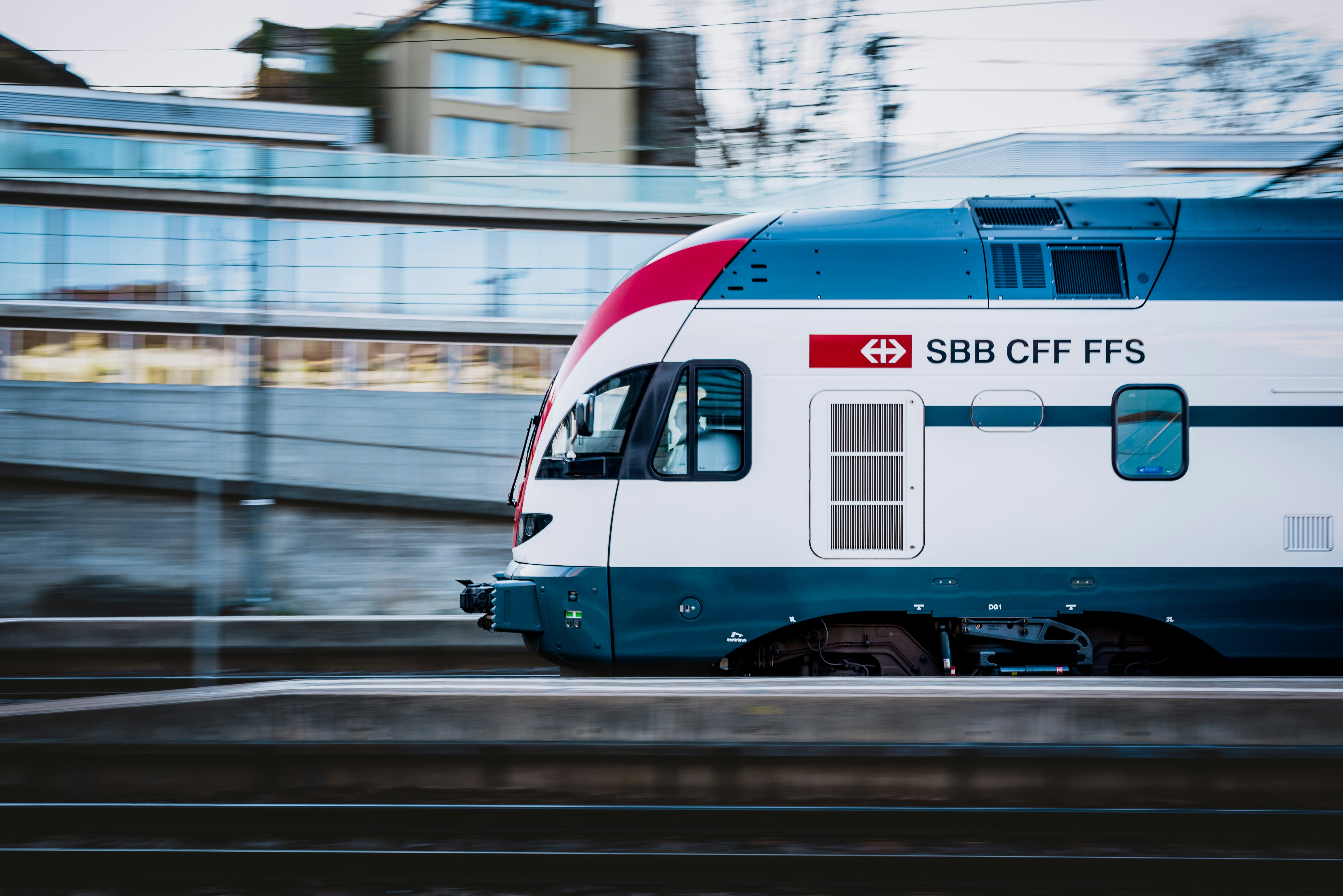 a train on the tracks, A Regional train leaving a station with an office building in the background