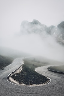 A winding mountain road disappearing into a misty forest at dusk.