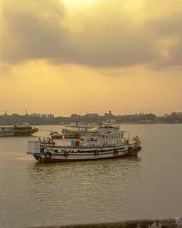 The confluence at Prayagraj with boats floating gently on the sacred rivers under a golden sky.
