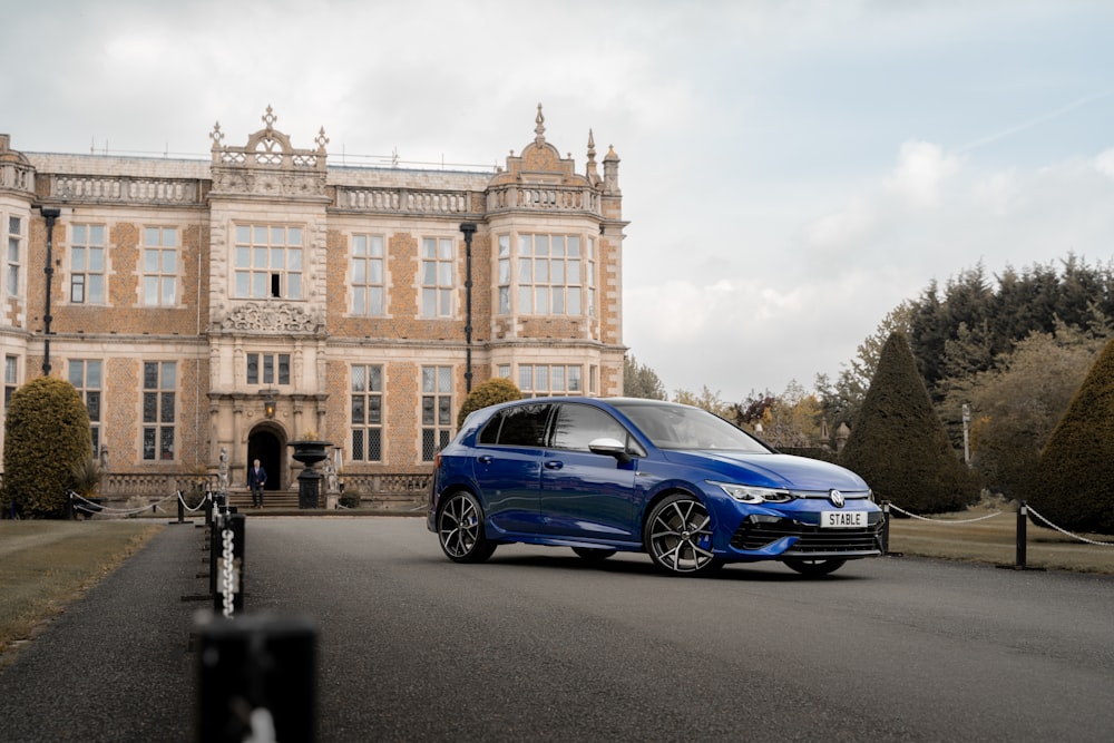 a blue car parked in front of a large building