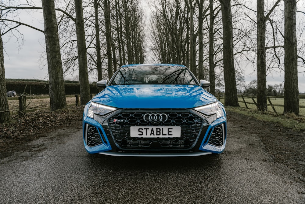 a blue sports car parked in a wooded area