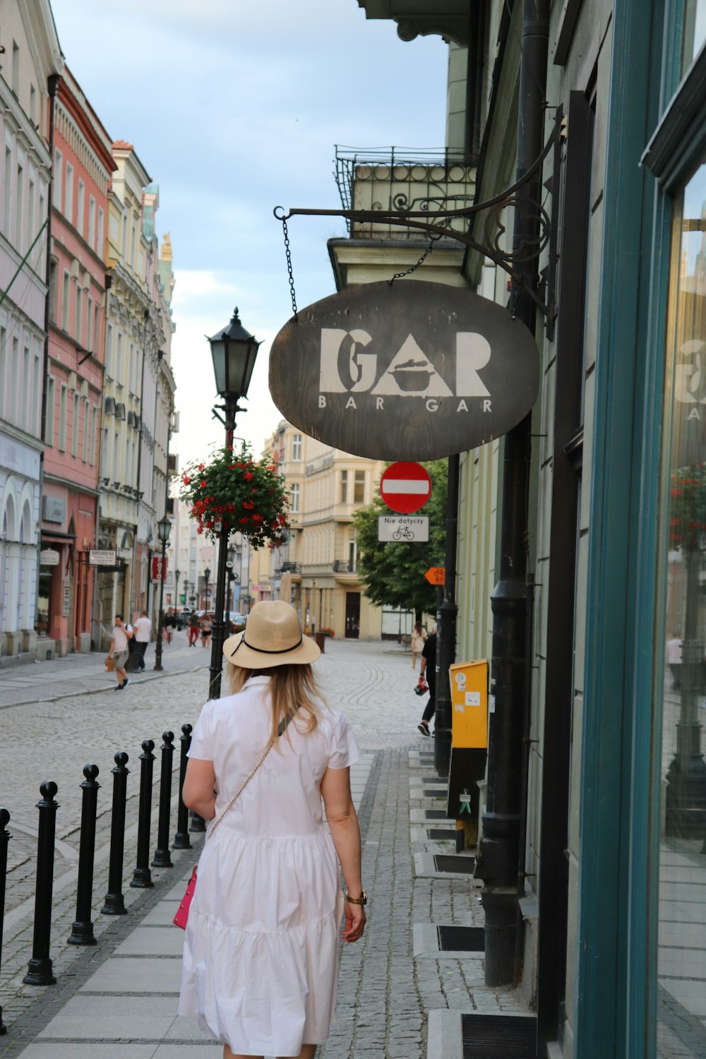 a person in a white dress walking down a sidewalk