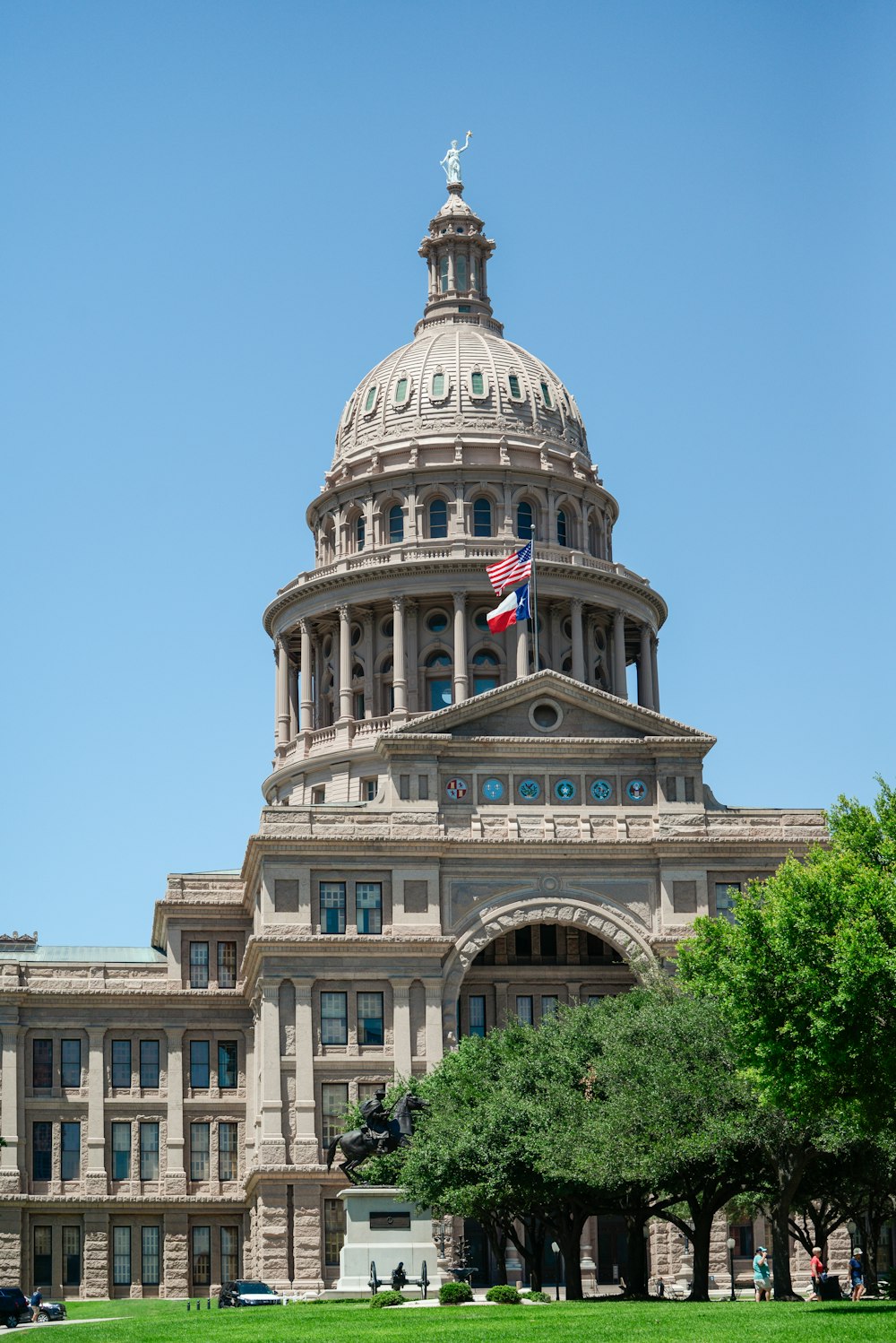 a large building with a flag on top with Texas State Capitol in the background