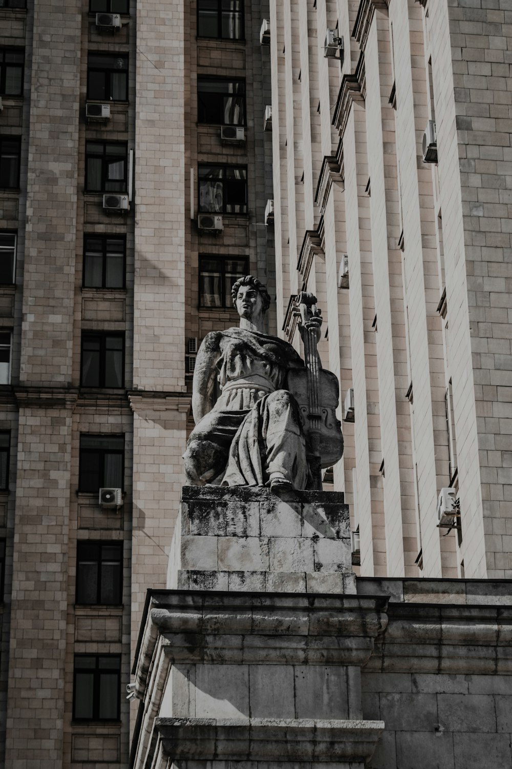 una estatua de una persona sosteniendo una bandera frente a un edificio