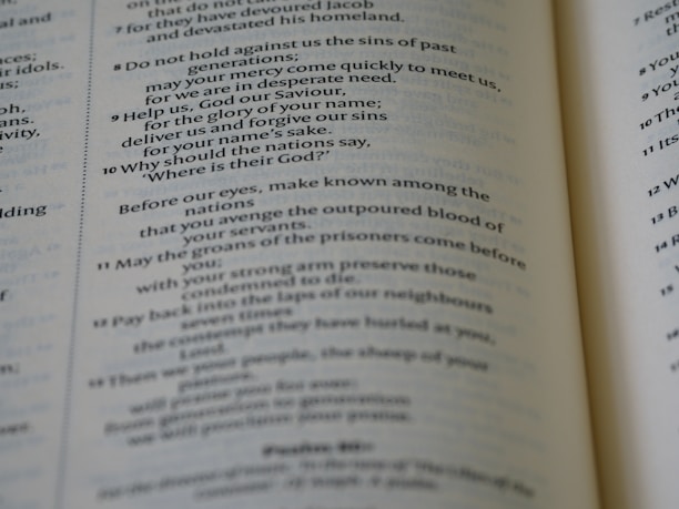 An open book displaying text in columns, with clear emphasis on verse numbers and religious content. The text is aligned in two columns on each page, with some parts italicized for emphasis.
