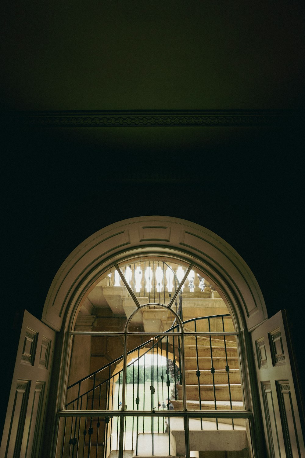 a large arched window with a metal railing and a building in the background
