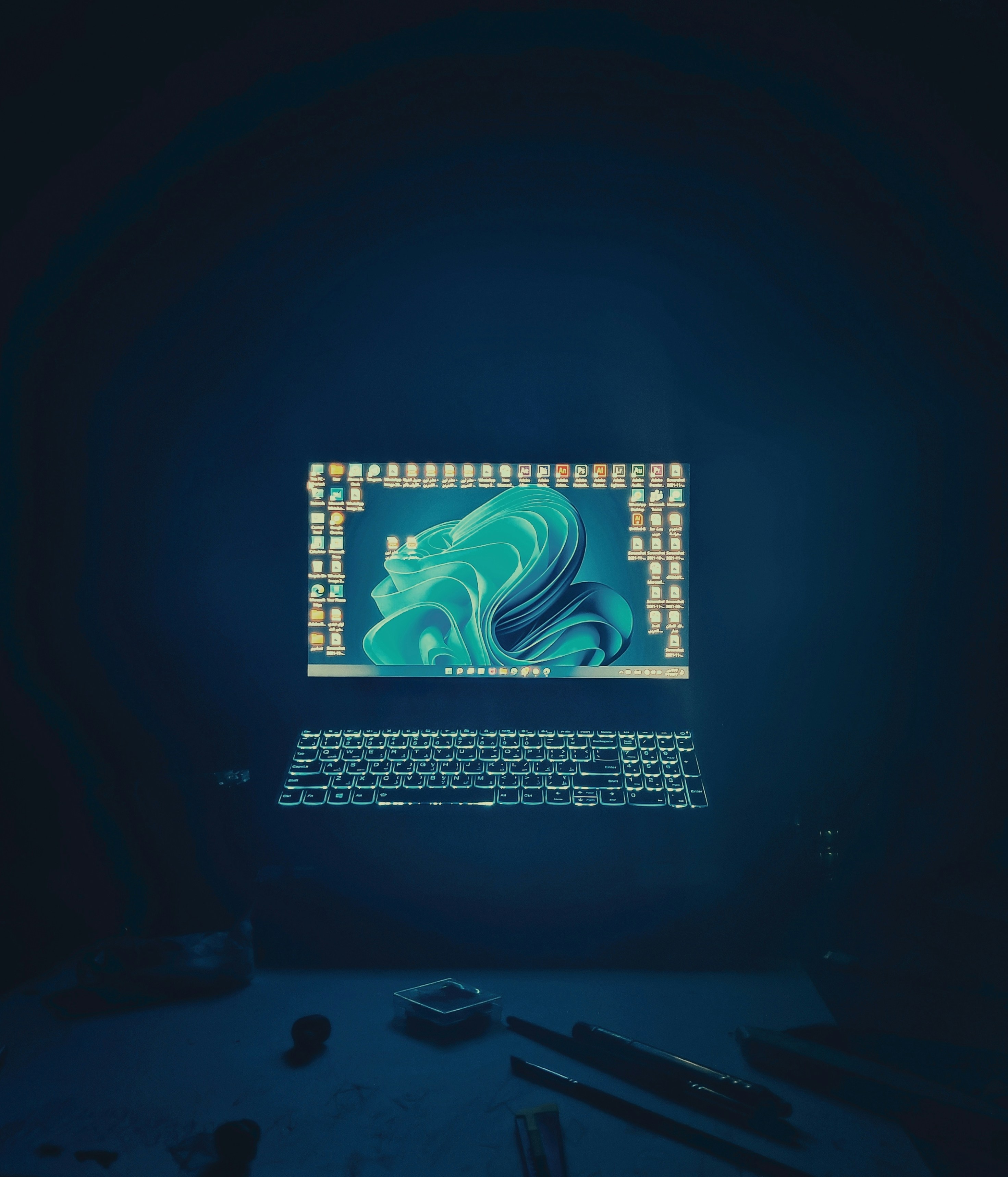 Modern open office at night with blue ambient lighting, empty desks with monitors glowing in dark atmospheric workspace