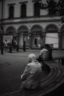 A cinematic image of an elderly person sitting on a bench, lost in thought with soft natural light.