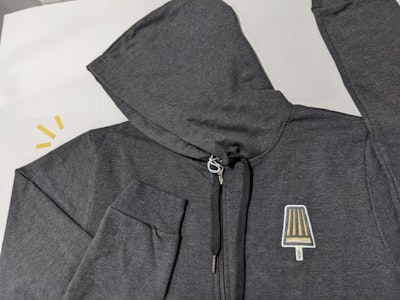 Light grey zip hoodie laid flat — photo by Submersible Tees on Unsplash
