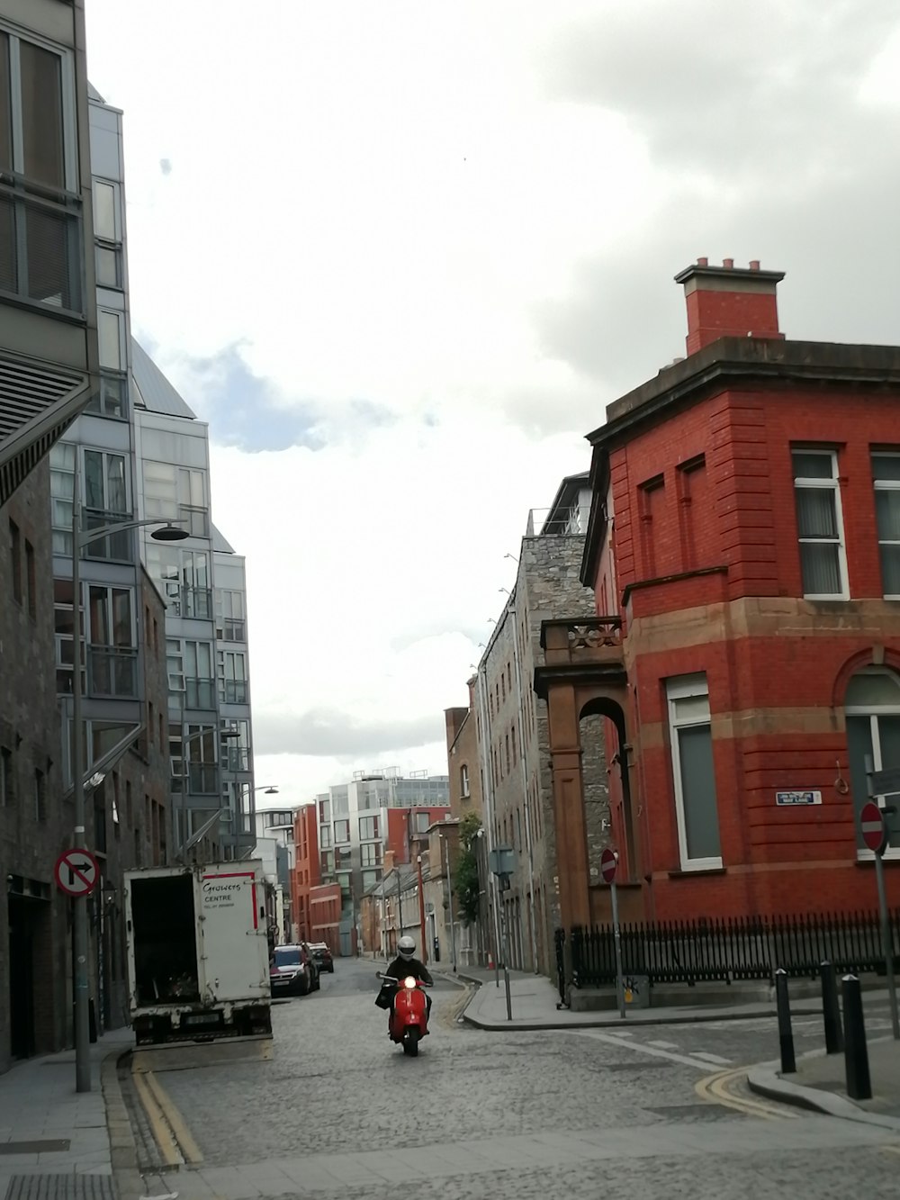 a person riding a motorcycle down a street between buildings