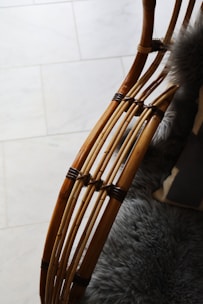 Curved wooden rods with a smooth finish are intricately woven and joined, possibly forming a part of furniture. A plush, grey furry blanket or cushion is visible, adding texture and warmth to the scene.