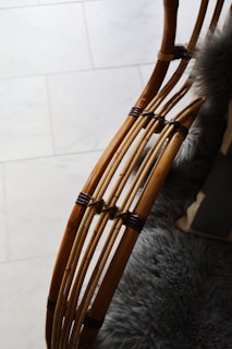 Curved wooden rods with a smooth finish are intricately woven and joined, possibly forming a part of furniture. A plush, grey furry blanket or cushion is visible, adding texture and warmth to the scene.