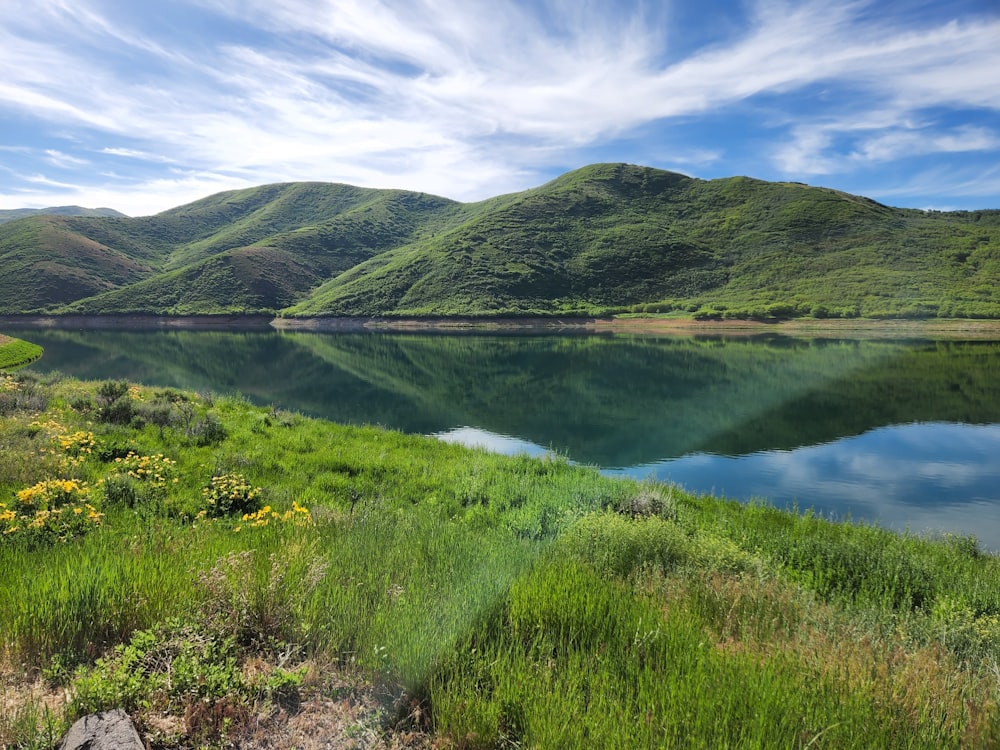 a lake surrounded by grass and hills